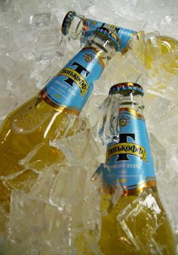 Фирменные бутылки пива Тинькофф Лайт среди кубиков льда - фото